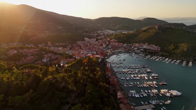 Vista aerea di un porto turistico con barche e colline.
