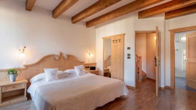 Camera da letto con travi in legno e arredamento chiaro.