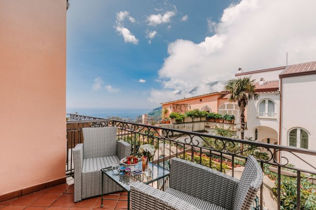 Balcone con vista mare e mobili intrecciati.