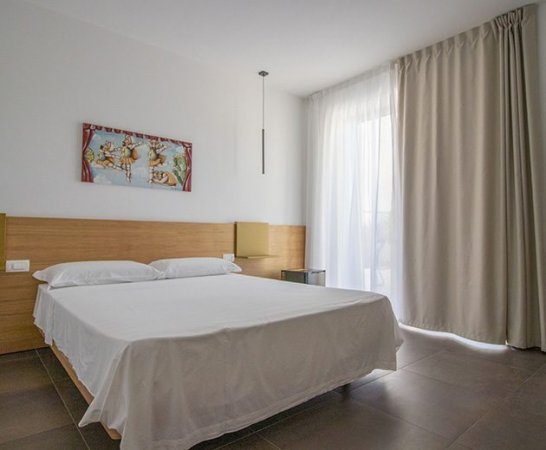 Letto matrimoniale in una stanza moderna con lenzuola bianche.