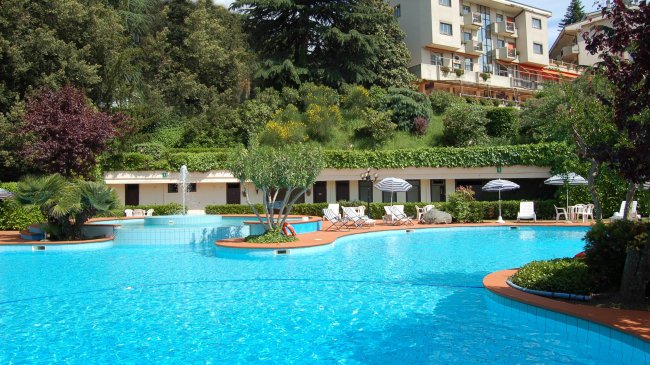 Piscina all'aperto con lettini e ombrelloni.