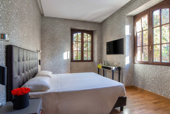 Camera con letto matrimoniale, pareti decorate, finestra luminoso.