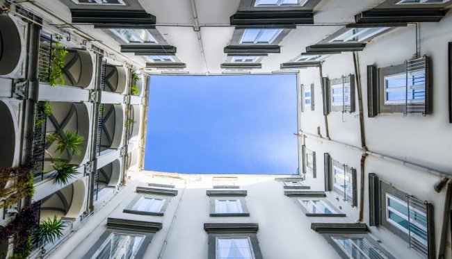 Cortile visto dal basso con cielo azzurro.