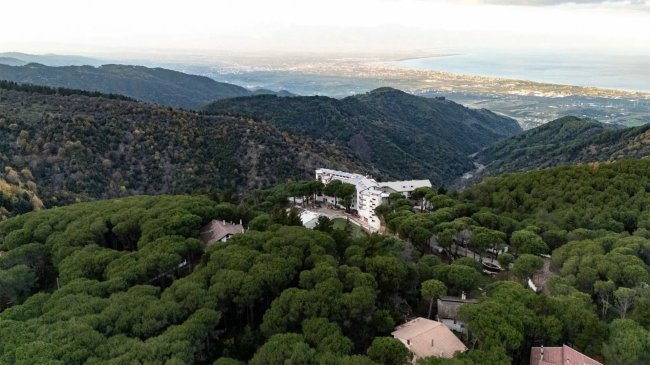 Montagna con foresta fitta e vista sul mare in lontananza.