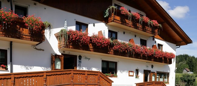 Edificio bianco con balconi pieni di fiori rossi.