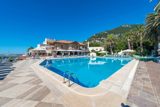 Piscina esterna con lettini e montagne sullo sfondo.