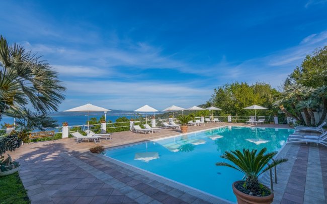 Piscina con lettini e ombrelloni, vista mare.