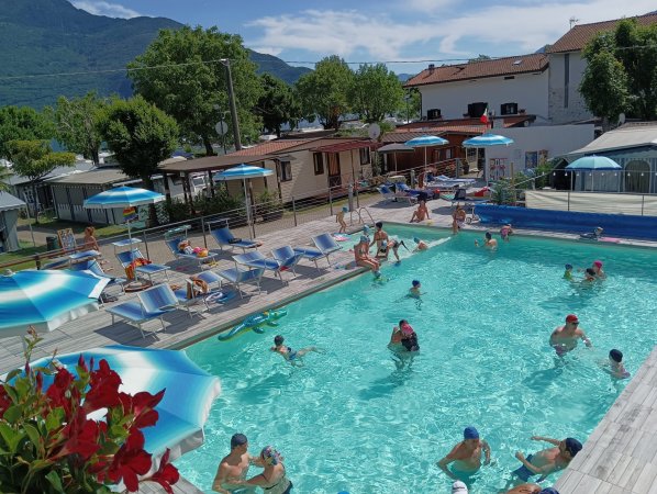 Piscina all'aperto con persone e ombrelloni.