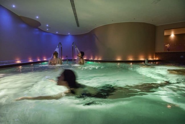 Una piscina interna con persone che nuotano sotto luci soffuse.