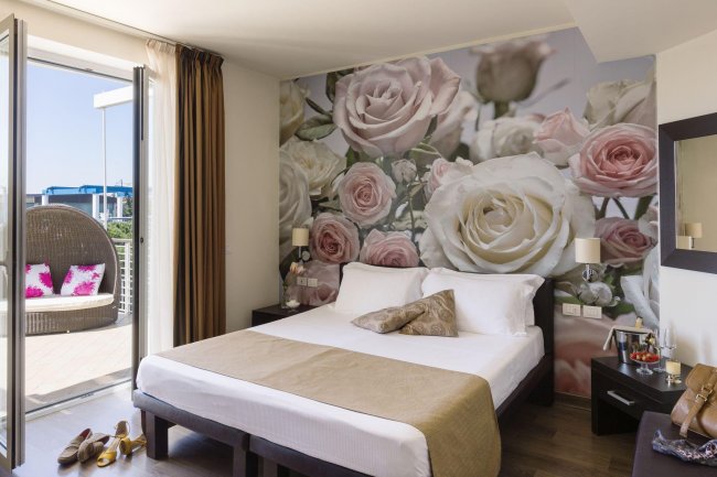 Camera con letto e sfondo di rose bianche e rosa.