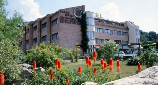 Hotel a tre piani con giardino fiorito.