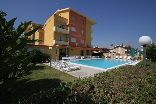 Esterno di un edificio con una piscina e sdraio.