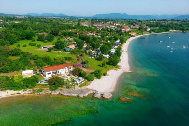 Vista aerea di una costa verdeggiante con spiaggia.