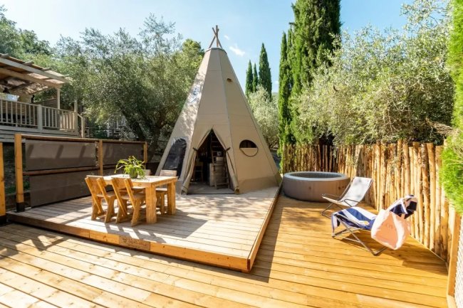 Un teepee su una terrazza di legno con tavolo e sedie.