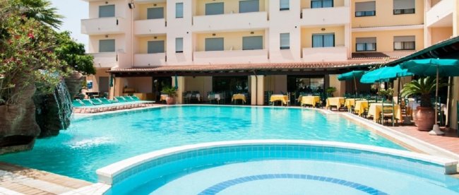 Piscina all'aperto con lettini e ombrelloni vicino a un edificio.