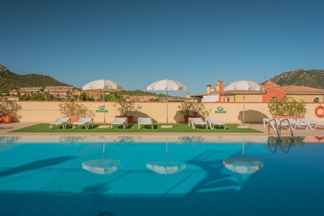 Piscina con lettini e ombrelloni bianchi.