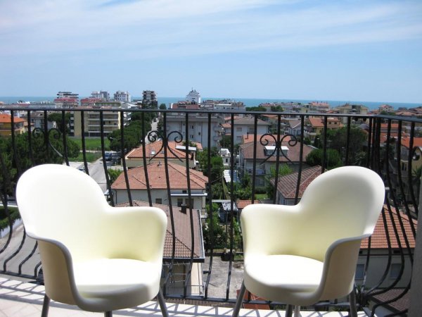 Due sedie su balcone con vista mare.
