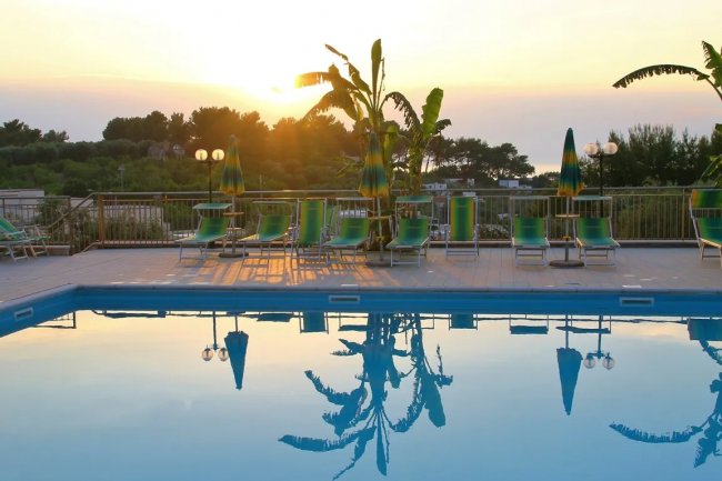 Piscina con lettini e ombrelloni al tramonto.