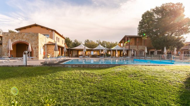 Piscina all'aperto con ombrelloni e prato verde.