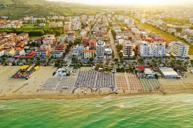 Veduta aerea di una spiaggia e edifici cittadini.