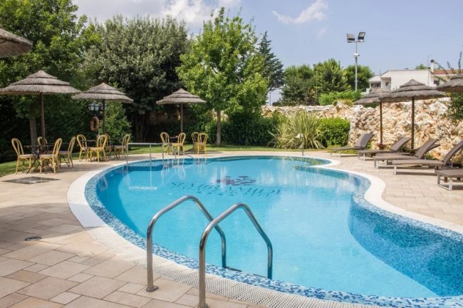 Piscina all'aperto con sedie e ombrelloni.