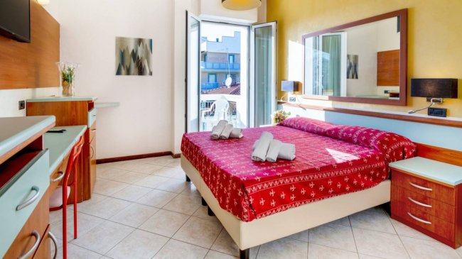 Camera con letto matrimoniale e porta finestra aperta.