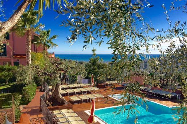 Piscina con lettini e vista mare tra gli ulivi.