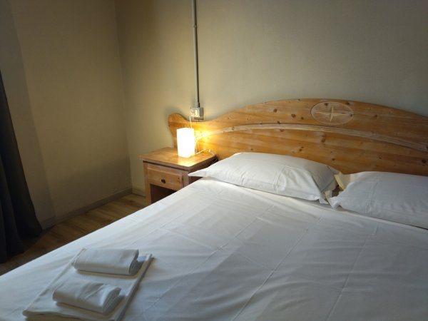 Letto matrimoniale con lenzuola bianche, lampada sul comodino.