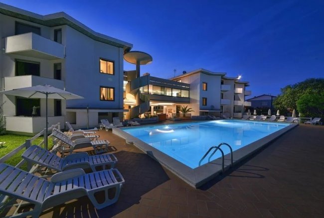 Piscina illuminata di notte accanto a edificio.