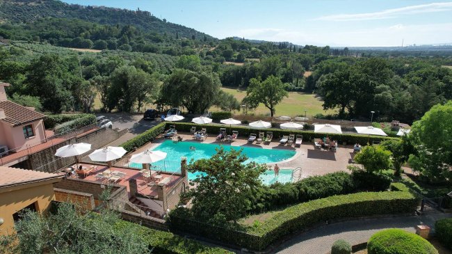 Piscina all'aperto circondata da siepi e natura.