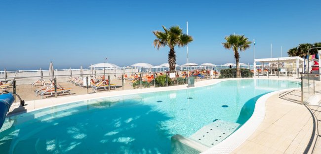 Piscina all'aperto con palme vicino alla spiaggia.