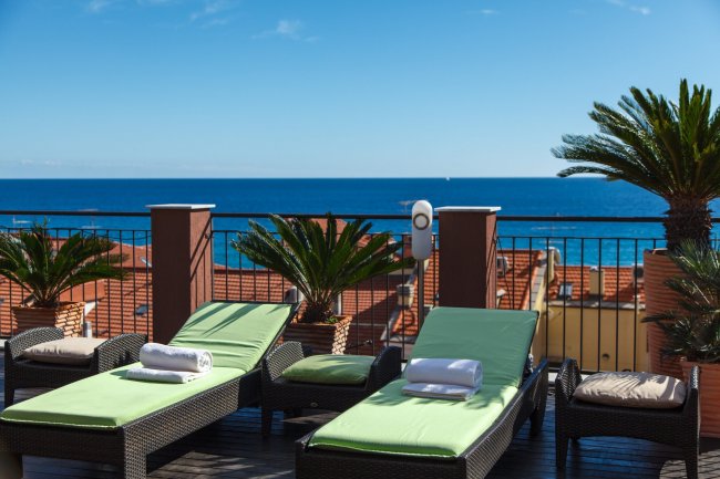 Lettini verdi su terrazza vista mare.