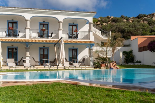 Vista esterna di un edificio bianco con piscina e giardino.