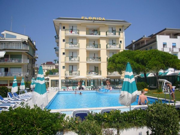 Hotel giallo con piscina e ombrelloni verdi.