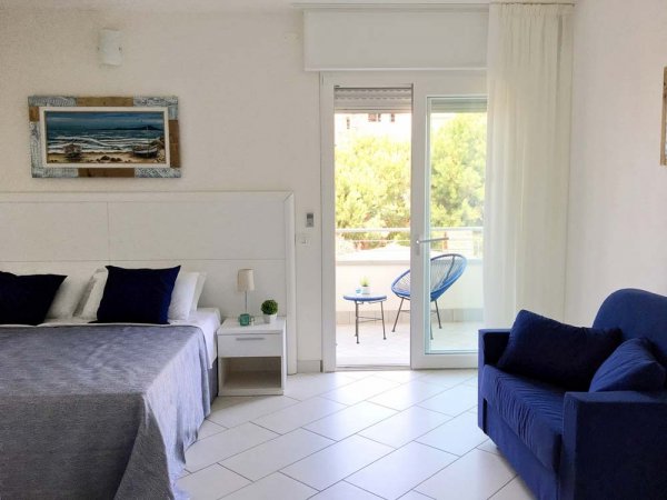 Stanza con letto, divano blu e balcone.