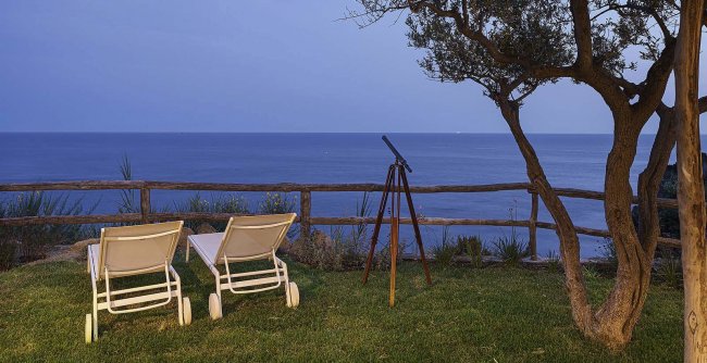 Due sedie a sdraio e telescopio con vista mare.