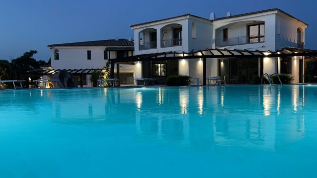 Un edificio bianco con piscina illuminata di notte.