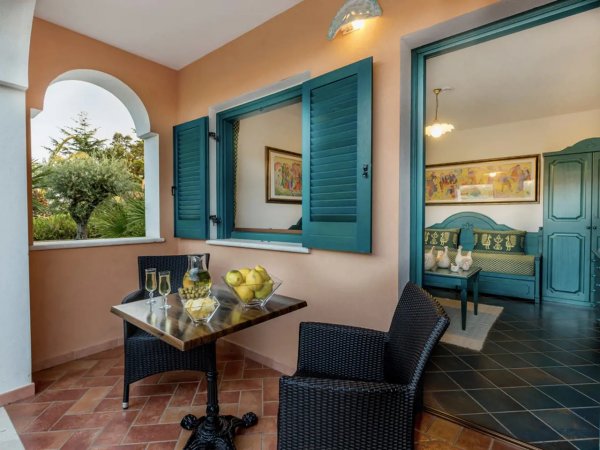 Terrazzino con tavolo, bicchieri e vista su una stanza interna.