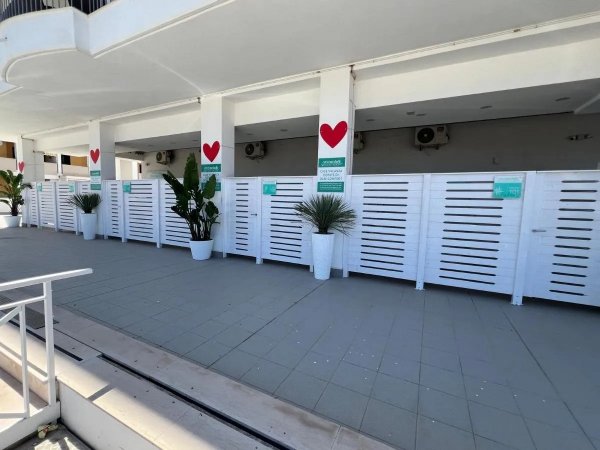 Corridoio esterno con pannelli e vasi decorativi.