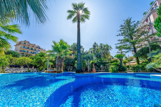 Piscina blu circondata da palme e vegetazione lussureggiante.
