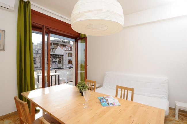 Sala con tavolo in legno e grande finestra aperta.