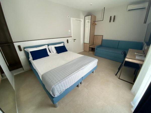 Stanza con letto matrimoniale, divano blu e scrivania.