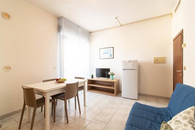 Soggiorno con tavolo, TV e frigorifero.