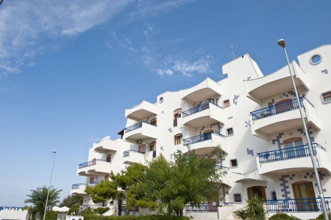 Edificio bianco con balconi blu e cielo sereno.