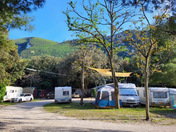 Campeggio con camper e tende, montagne sullo sfondo.