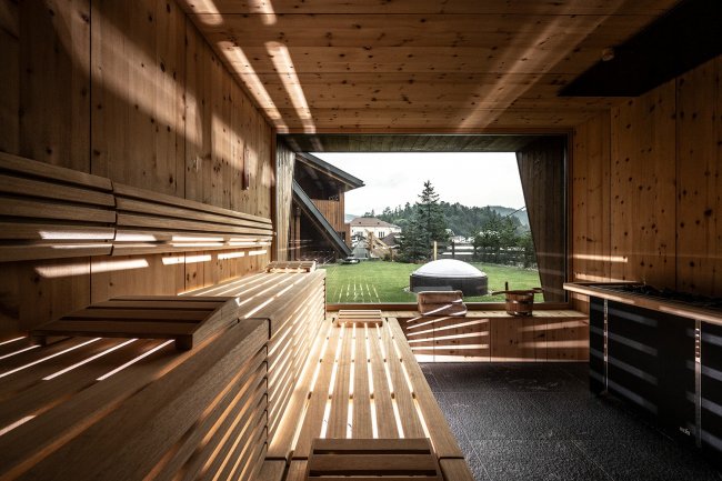 Interno di una sauna in legno con vista sul prato.
