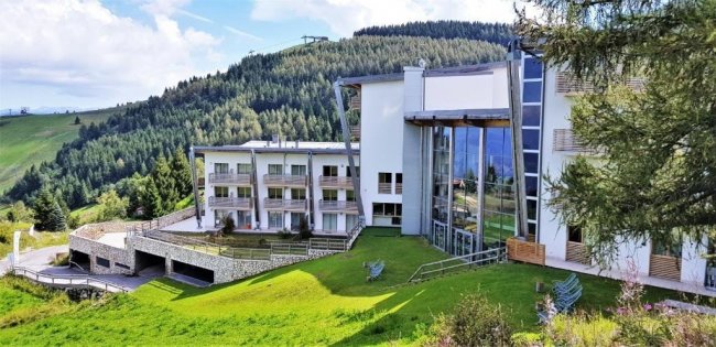 Edificio moderno circondato da colline verdi.