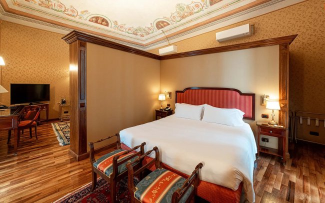 Camera d'hotel con letto matrimoniale e decorazioni classiche.