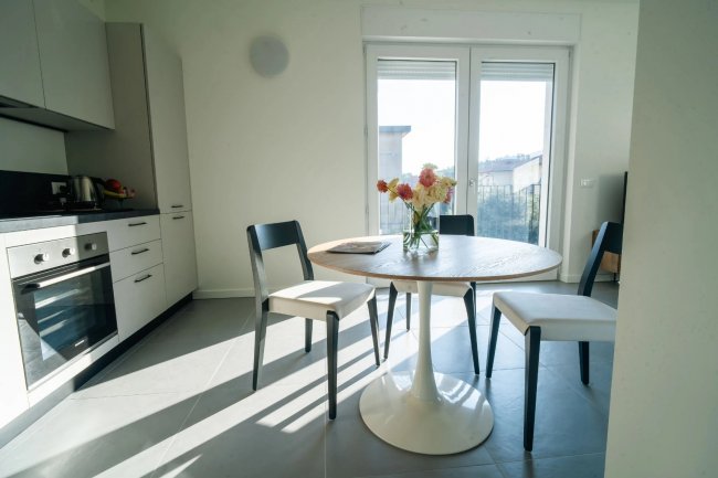 Un tavolo rotondo con fiori in una cucina moderna e luminosa.