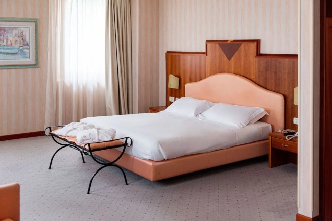 Camera d'hotel con letto matrimoniale e comodini.